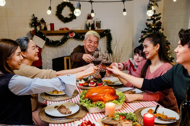 Un grupo feliz y alegre de la familia extendida asiática tiene un brindis y alegría durante la cena de Navidad