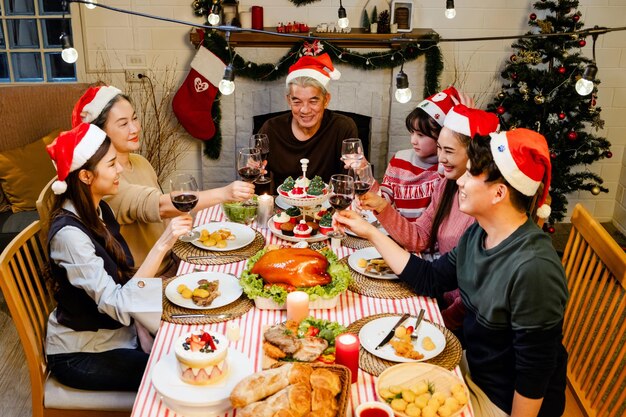 Un grupo feliz y alegre de la familia extendida asiática tiene un brindis y alegría durante la cena de Navidad