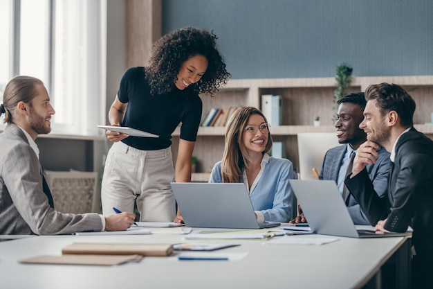 Un grupo feliz de empresarios discutiendo la estrategia durante una reunión de equipo en el escritorio juntos