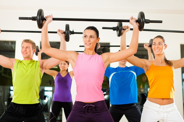 Grupo de fitness con barra en el gimnasio