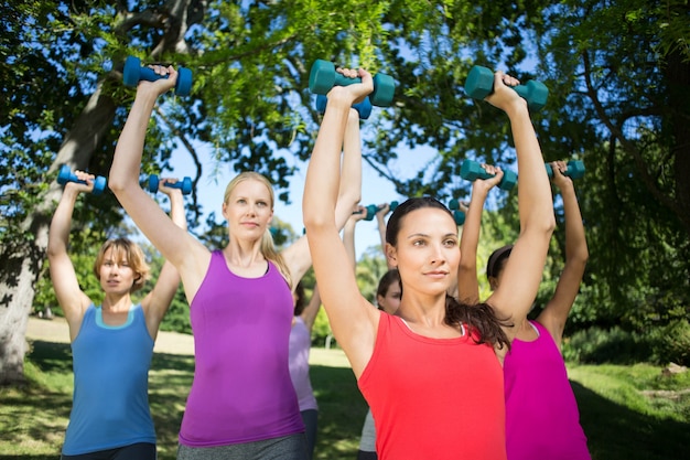 Grupo de fitness levantando pesas de mano en el parque