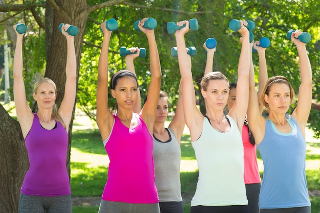 Grupo de fitness levantando pesas de mano en el parque