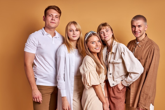 Grupo fotogénico de jóvenes posando en elegante traje acogedor, sesión de estudio