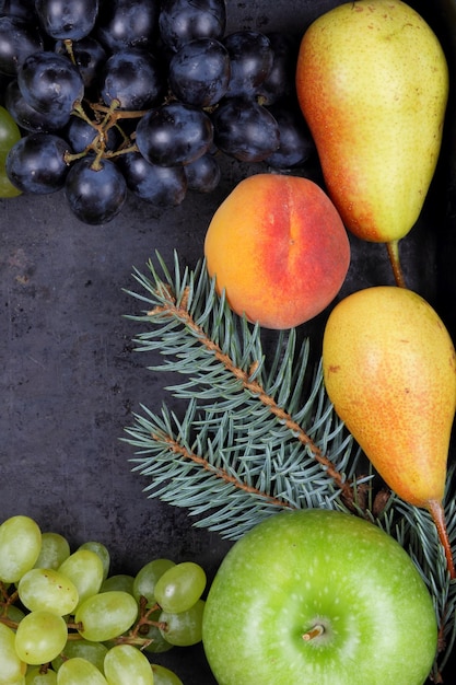 Un grupo de frutas y bayas de colores saludables con ramas de abeto sobre un fondo oscuro Acogedor bodegón de invierno Vista desde arriba Primer plano