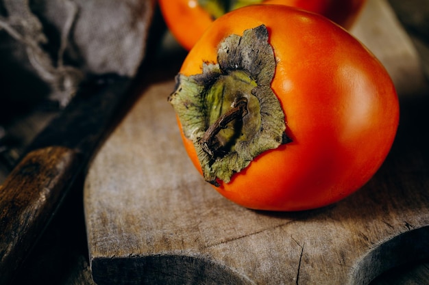 Un grupo de frutas maduras de caqui naranja Frutas de caqui sobre un fondo rústico de tablero de madera