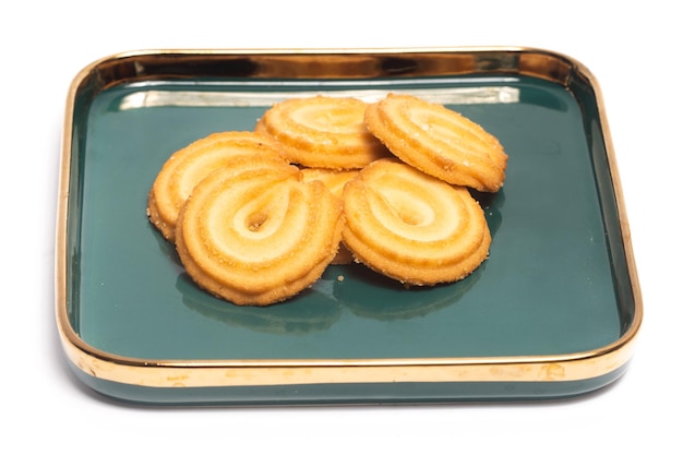 Grupo de galletas de mantequilla danesa la galleta de anillo de vainilla en un plato verde aislado sobre un fondo blanco