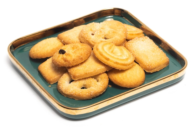 Grupo de galletas de mantequilla danesa en un plato verde aislado sobre un fondo blanco