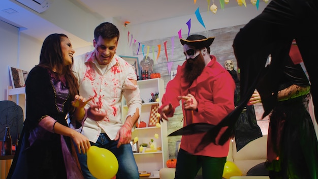 Grupo de gente alegre vestida para halloween bailando en una fiesta salvaje.