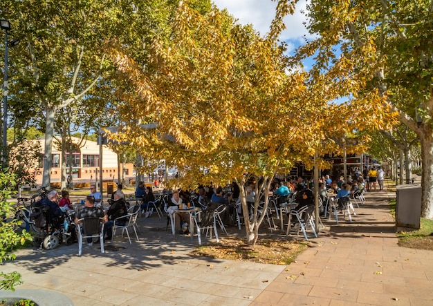 Grupo de gente disfrutando del vermú tomando unas tapas en una plaza de unos bulevares