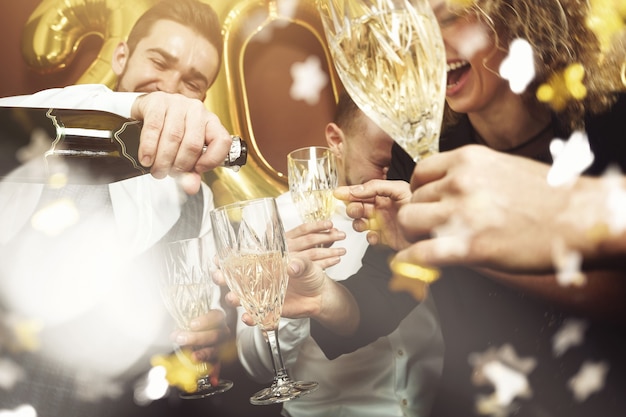 Grupo de gente hermosa fiesta bien vestida celebrando el año nuevo y bebiendo vino espumoso