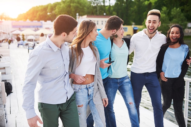 Grupo de gente joven y exitosa sonriente de vacaciones en el muelle.