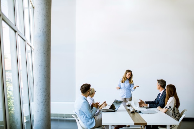 Grupo de gente de negocios con adultos jóvenes y colega senior en reunión en el interior de la oficina moderna y luminosa