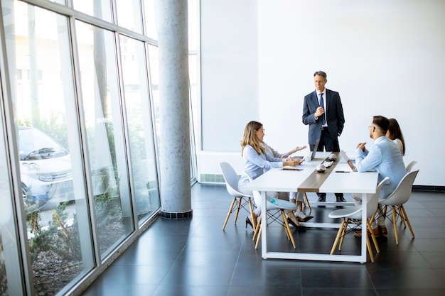 Grupo de gente de negocios con adultos jóvenes y colega senior en reunión en el interior de la oficina moderna y luminosa