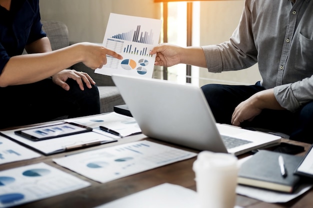 Grupo de gente de negocios exitosa discutir el papeleo y el uso de un ordenador portátil juntos, el trabajo en equipo y el concepto de lluvia de ideas.