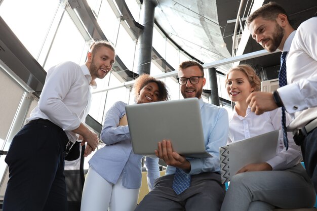 Grupo de gente de negocios moderna trabajando juntos en la oficina creativa mientras está de pie cerca del escritorio.