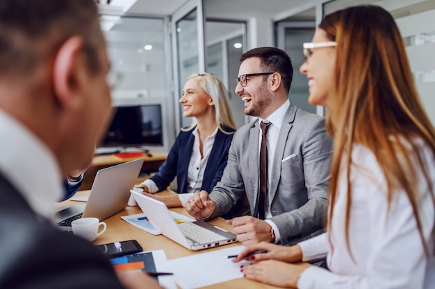 Grupo de gente de negocios positiva sentada en la sala de juntas y de intercambio de ideas.