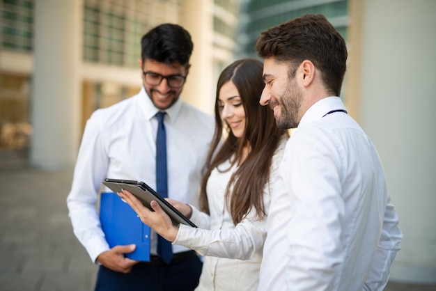 Grupo de gente de negocios usando una tableta fuera de su oficina, concepto de trabajo en equipo