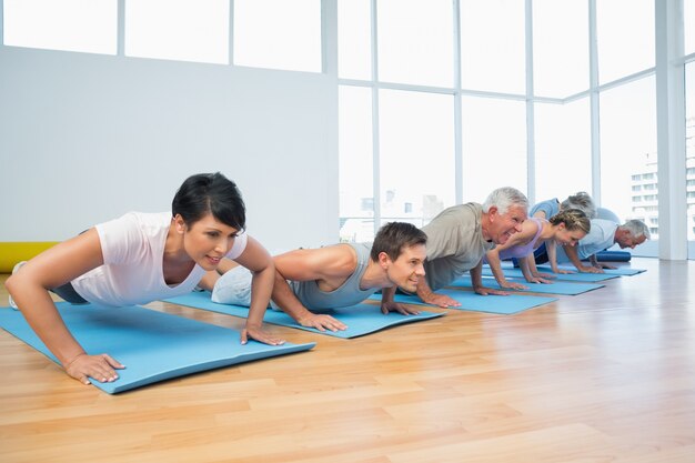 Grupo haciendo flexiones en fila en la clase de yoga