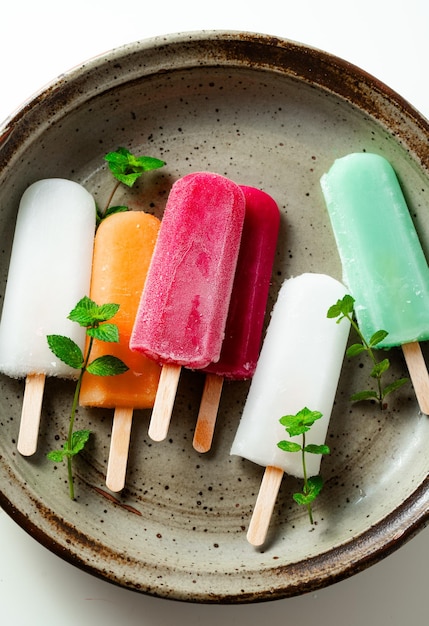 Grupo de helados de colores en un palo en un postre blanco de verano