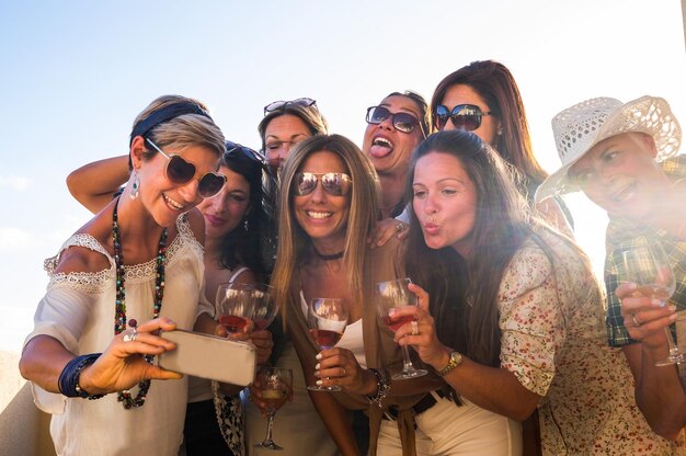 Grupo de hermosas mujeres caucásicas disfrutando de un aperitivo en la terraza celebrando un cumpleaños Tome un selfie para amigos ausentes con grandes sonrisas