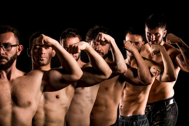 Foto grupo de hombre musculoso deportivo sin camisa posando sobre fondo oscuro