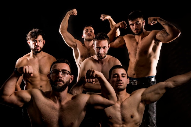 Foto grupo de hombre musculoso deportivo sin camisa posando sobre fondo oscuro