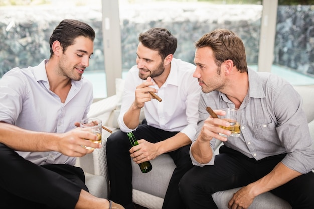 Grupo de hombres fumando y bebiendo mientras discute