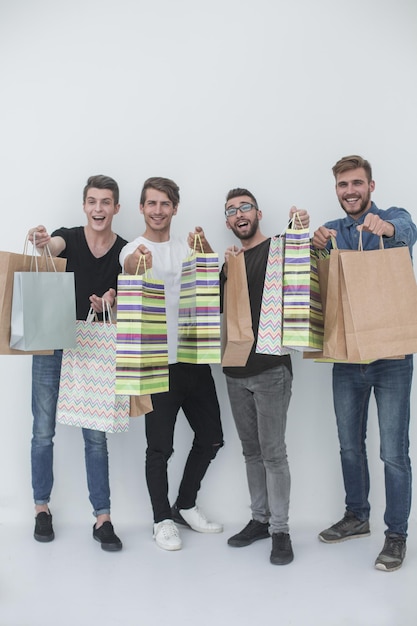 Grupo de hombres jóvenes muestra foto de bolsas de compras con espacio de copia