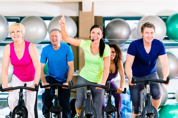 Grupo de hombres y mujeres girando en bicicletas de fitness en el gimnasio