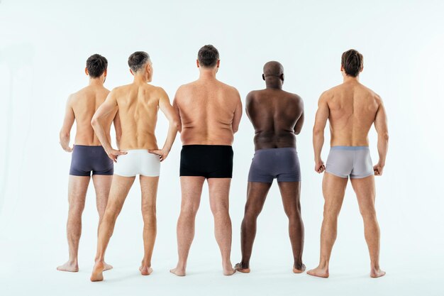 Grupo de hombres multiétnicos posando para un conjunto de belleza positiva corporal de edición masculina. Chicos sin camisa con diferentes edades y cuerpo usando ropa interior de boxeadores