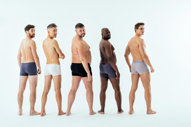 Grupo de hombres multiétnicos posando para un conjunto de belleza positiva corporal de edición masculina. Chicos sin camisa con diferentes edades y cuerpo usando ropa interior de boxeadores