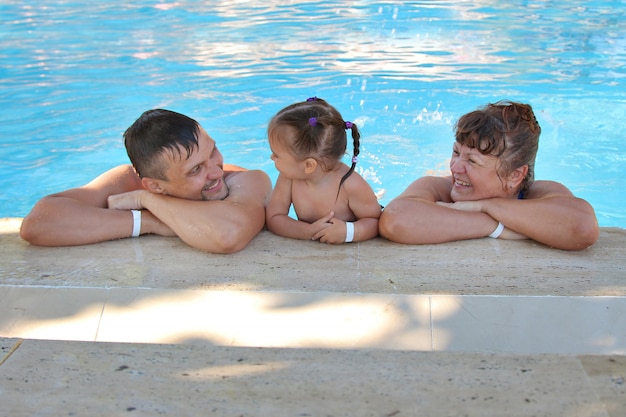 Un grupo de hombres nadando en la piscina. hombre mujer y niño en vacaciones.