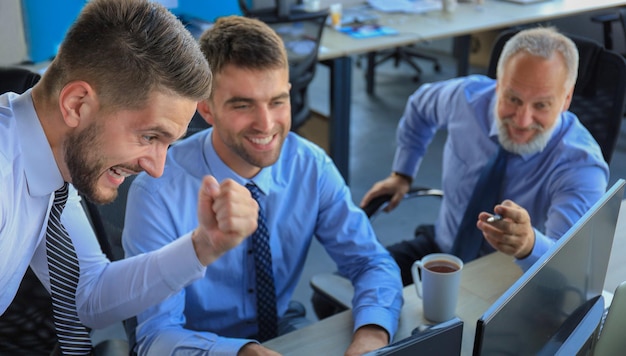 Grupo de hombres de negocios modernos en ropa formal sonriendo y gesticulando mientras trabajan en la oficina