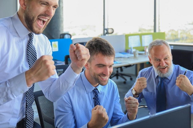 Grupo de hombres de negocios modernos en ropa formal sonriendo y gesticulando mientras trabajan en la oficina