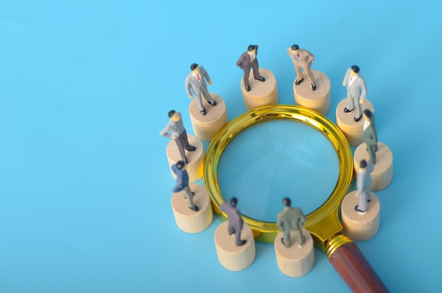 Un grupo de hombres de negocios de pie juntos frente a una lupa simboliza su enfoque en el análisis en profundidad de las tendencias del mercado y las oportunidades de negocio