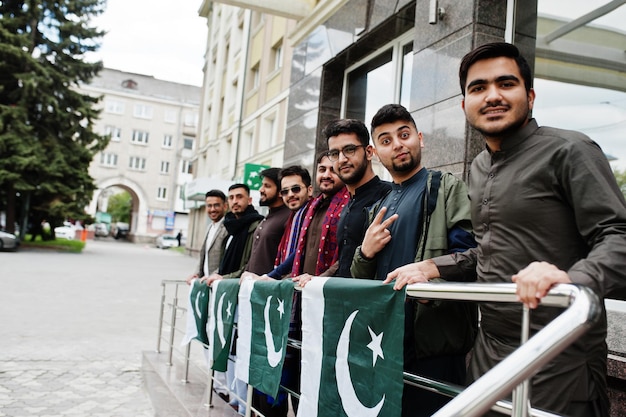 Grupo de hombres paquistaníes vestidos con ropa tradicional salwar kameez o kurta con banderas de Pakistán