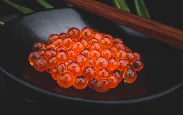 Grupo de huevas de salmón con poca iluminación y fondo negro.