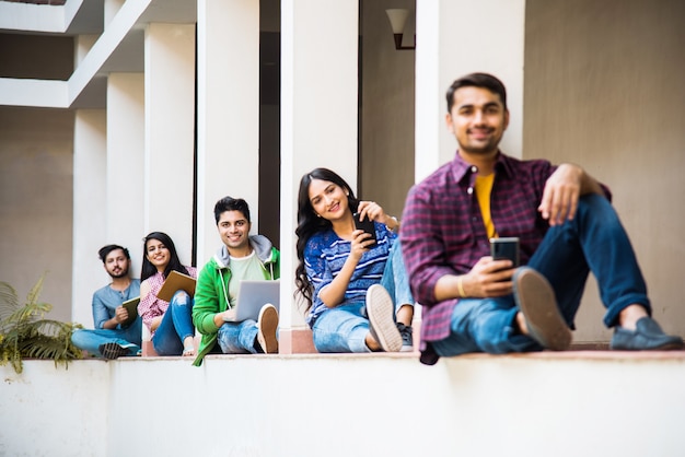 Grupo indiano asiático de estudantes universitários usando smartphones para redes sociais, enviando mensagens de texto, assistindo a vídeos