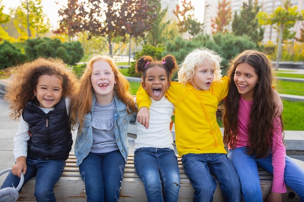 Grupo inter-racial de crianças, meninas e meninos brincando juntos no parque no dia de verão