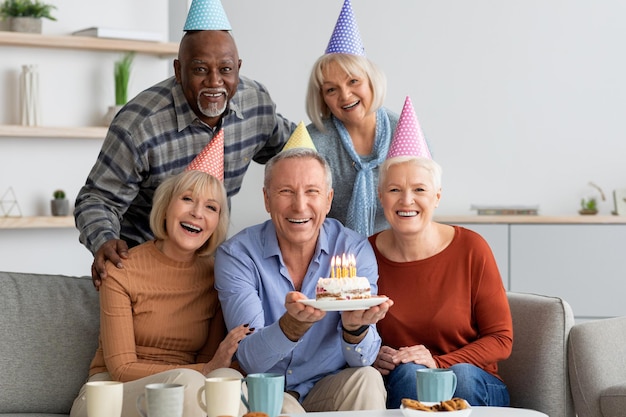 Grupo internacional de personas mayores que tienen fiesta de cumpleaños en casa