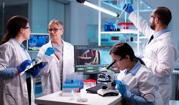 Grupo de investigadores en el laboratorio de salud estudia el virus para descubrir la vacuna Investigadores químicos que trabajan en el laboratorio con alta tecnología analizan el descubrimiento de muestras de sangre y material genético,