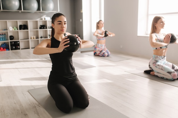 Grupo de joven atractiva deportiva practicando pilates. Personas de pie juntas. Haciendo ejercicio