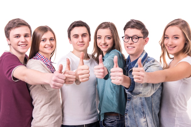 Grupo joven sonriente feliz de amigos con los pulgares para arriba.