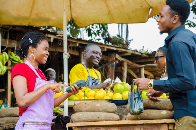 Grupo de jóvenes africanos que realizan transacciones en un mercado.