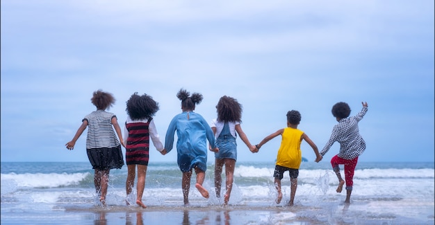 Foto grupo de jóvenes afroamericanos niños corriendo en la playa.