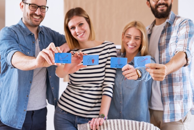 Grupo de jóvenes alegres felices con pegatinas de notas azules con imágenes prediseñadas para negocios exitosos.