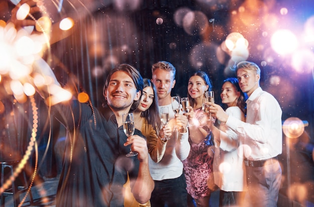 Grupo de jóvenes alegres tienen fiesta y celebración de año nuevo en el interior.