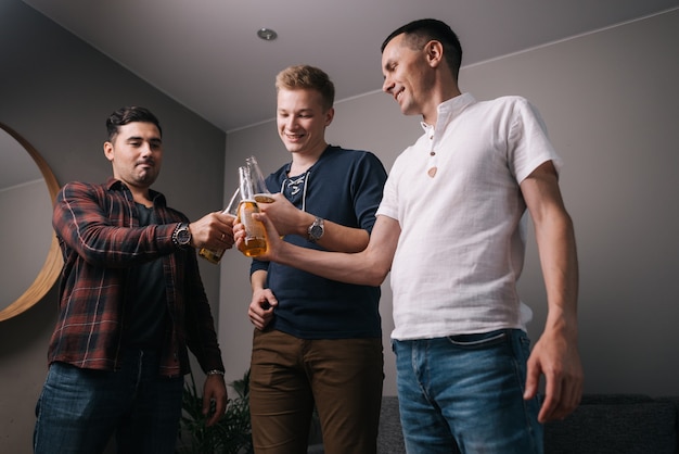 Grupo de jóvenes alegres tintineo de botellas de cerveza