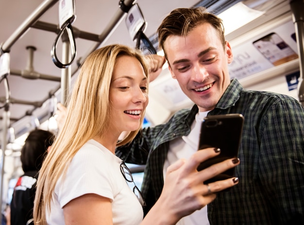 Grupo de jóvenes amigos adultos que usan teléfonos inteligentes en el metro