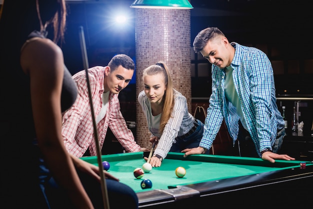 Grupo de jóvenes amigos alegres jugando billar.